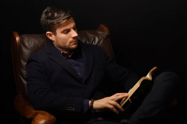 closeup-shot-mature-man-elegant-suit-sitting-leather-couch-reading-book_181624-35826